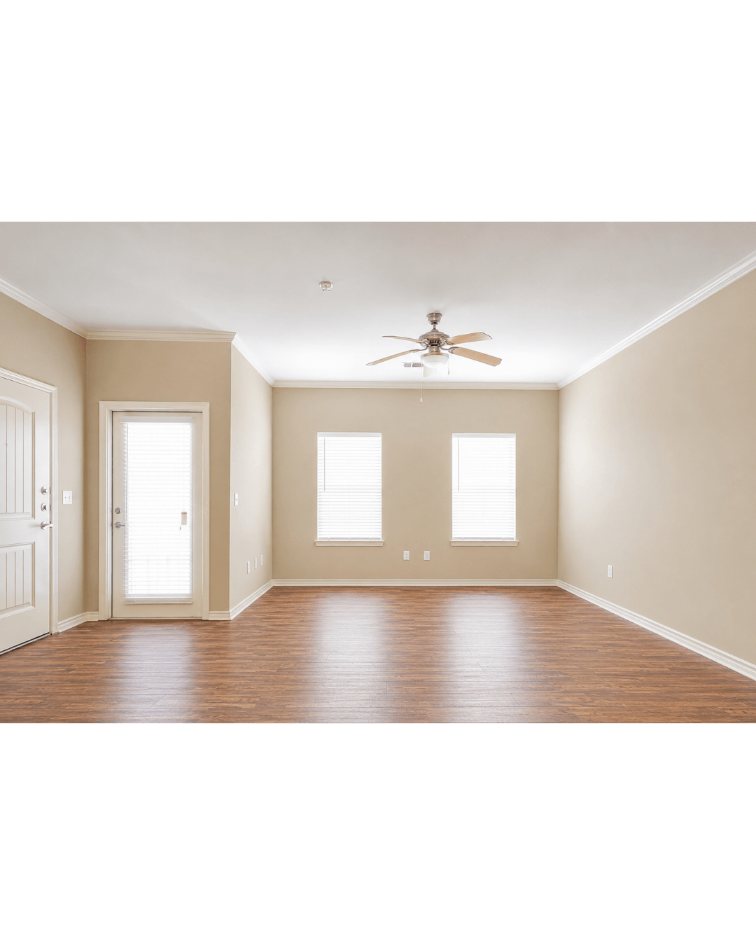 A room with a ceiling fan and three windows.